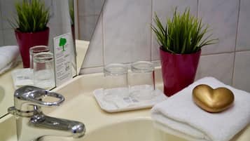 A bathroom with a sink, two potted plants, a golden soap dish, and a white towel.