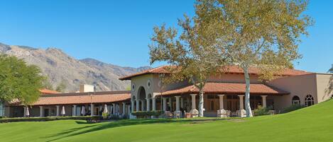 A building with a red-tiled roof, columns, and a lawn in front.
