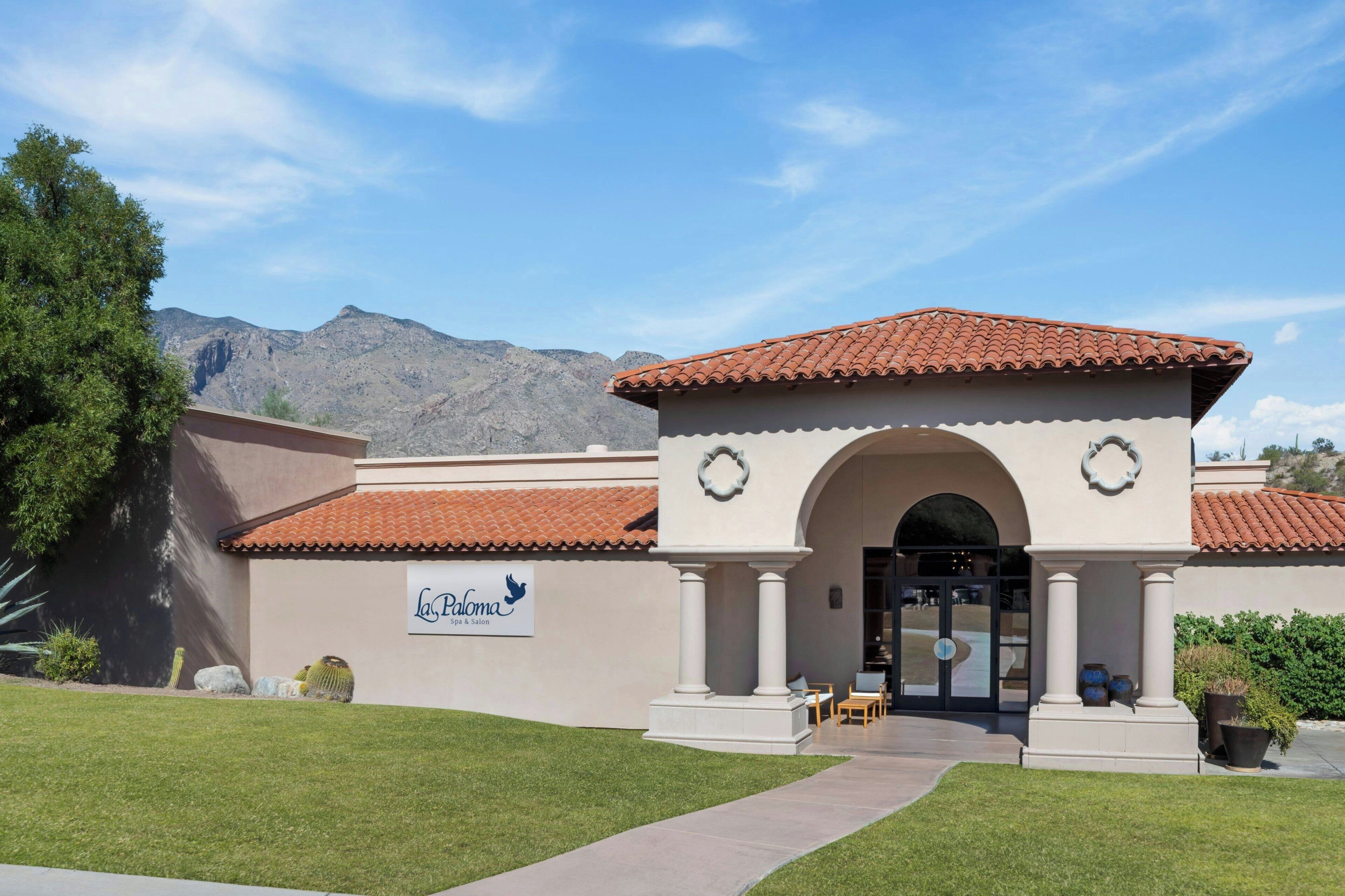 A spa and salon building with a tiled roof, an arched entrance, and a sign reading "La Paloma Spa & Salon."