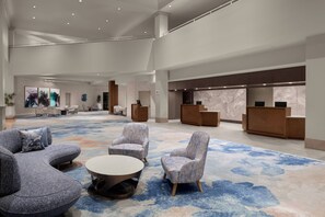 A spacious lobby with a large carpeted area, seating arrangements, and reception desks.