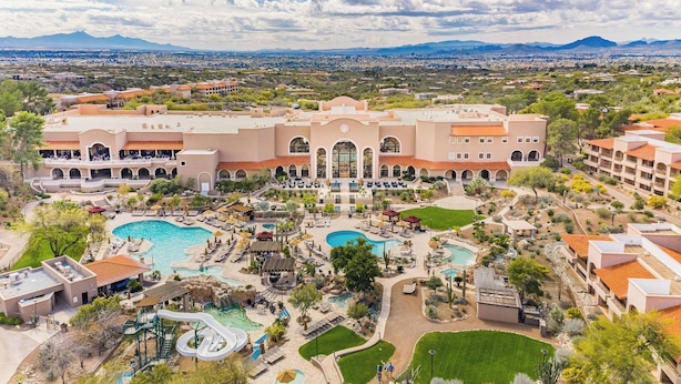 Un complexe hôtelier doté de plusieurs piscines, d’un grand bâtiment central et situé dans un cadre montagneux.