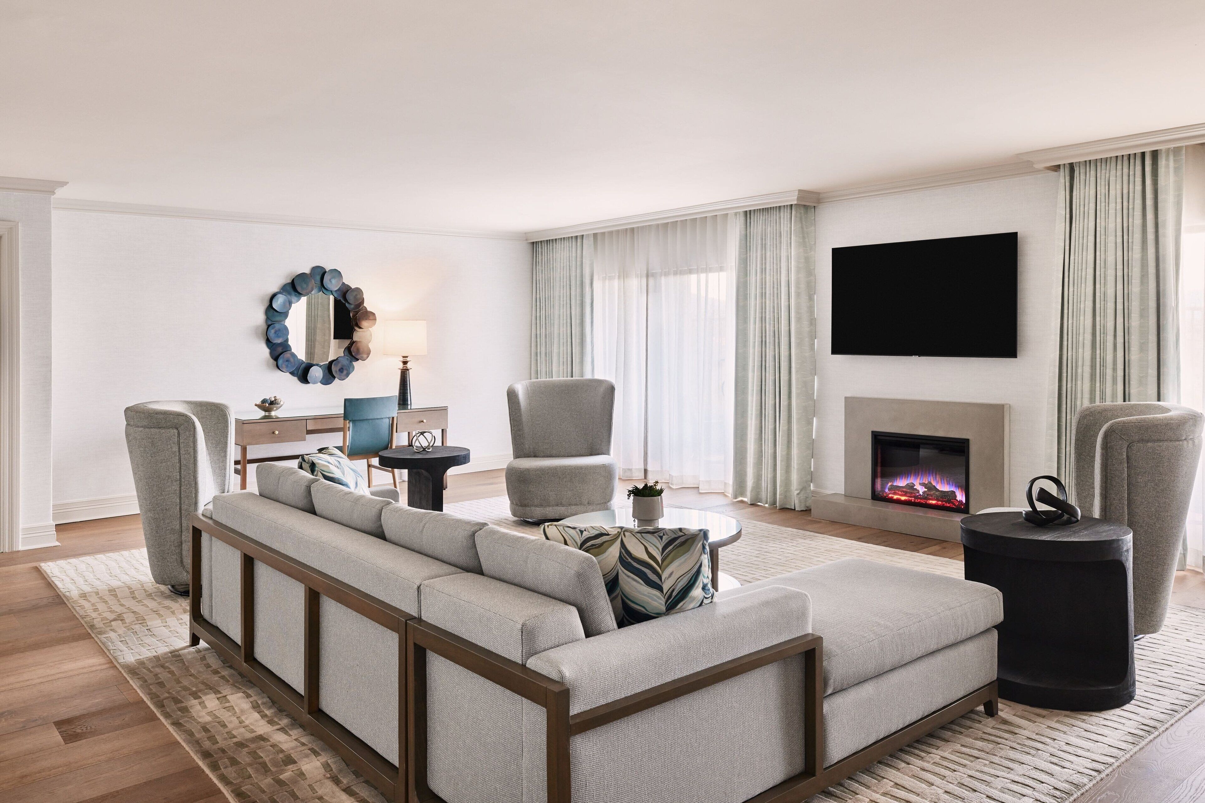 A modern living room with a sectional sofa, armchairs, a coffee table, and a fireplace.