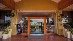 A hotel entrance with a glass door, potted plants, and a tiled floor. - Holiday Inn La Piedad by IHG (La Piedad)