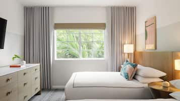 A hotel room with a bed, a bedside table with a lamp, a TV on the wall, and a window with curtains.