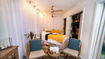 Relax in a stylish room with a large bed, wicker chairs, and a small table.