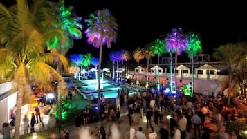 A crowded outdoor pool area with palm trees and a pool.