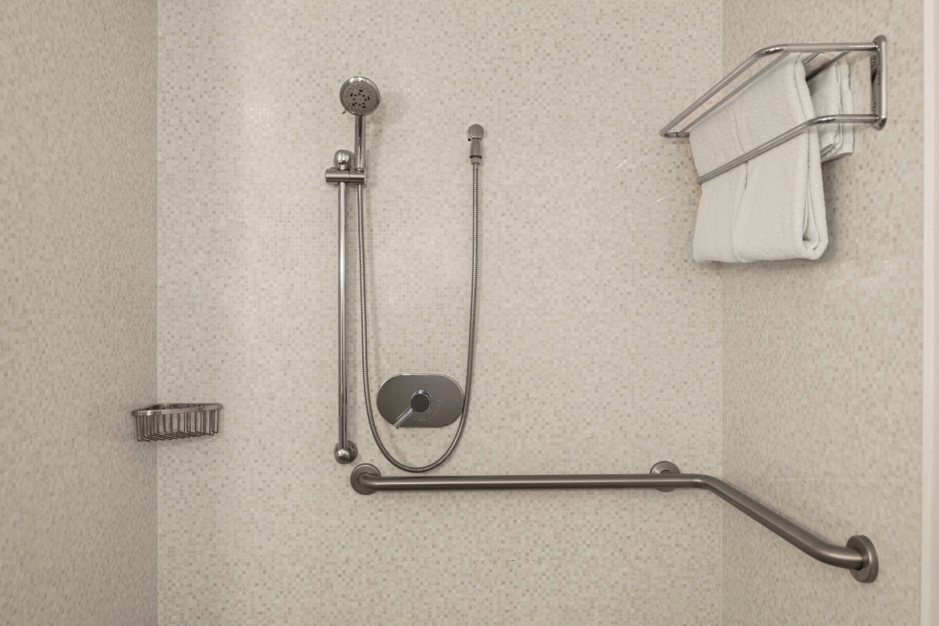 A bathroom with a shower, grab bar, towel rack, and a soap dish.