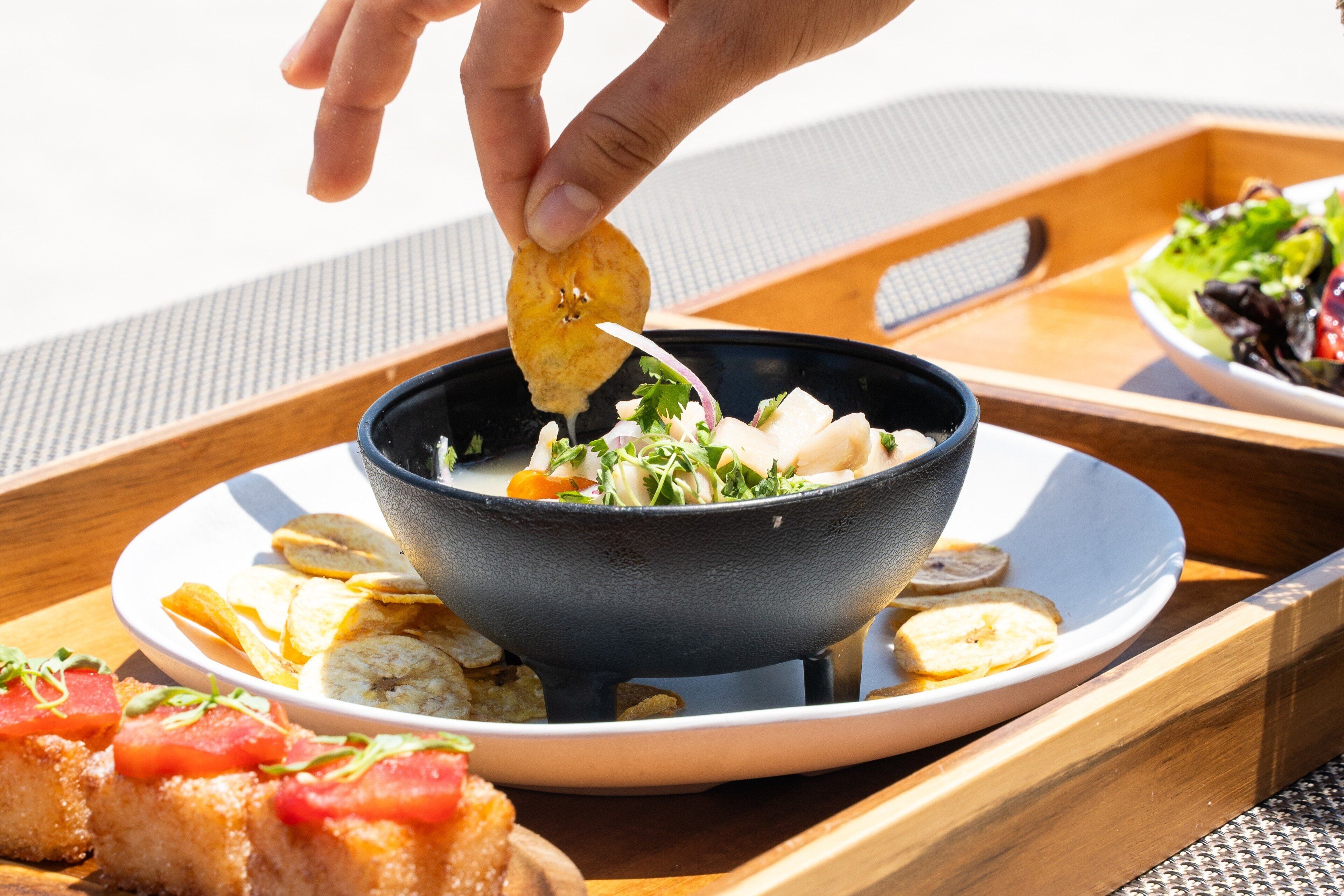 A meal tray with a bowl of soup, a plate of chips, and a piece of grilled fish.