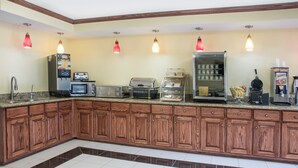 A kitchen with wooden cabinets, granite countertops, and various appliances including a coffee maker, toaster, and refrigerator. - Days Inn by Wyndham Houston (Houston)