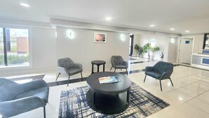 A modern lobby with a round black table, grey armchairs, and a large window. - Days Inn by Wyndham Houston (Houston)