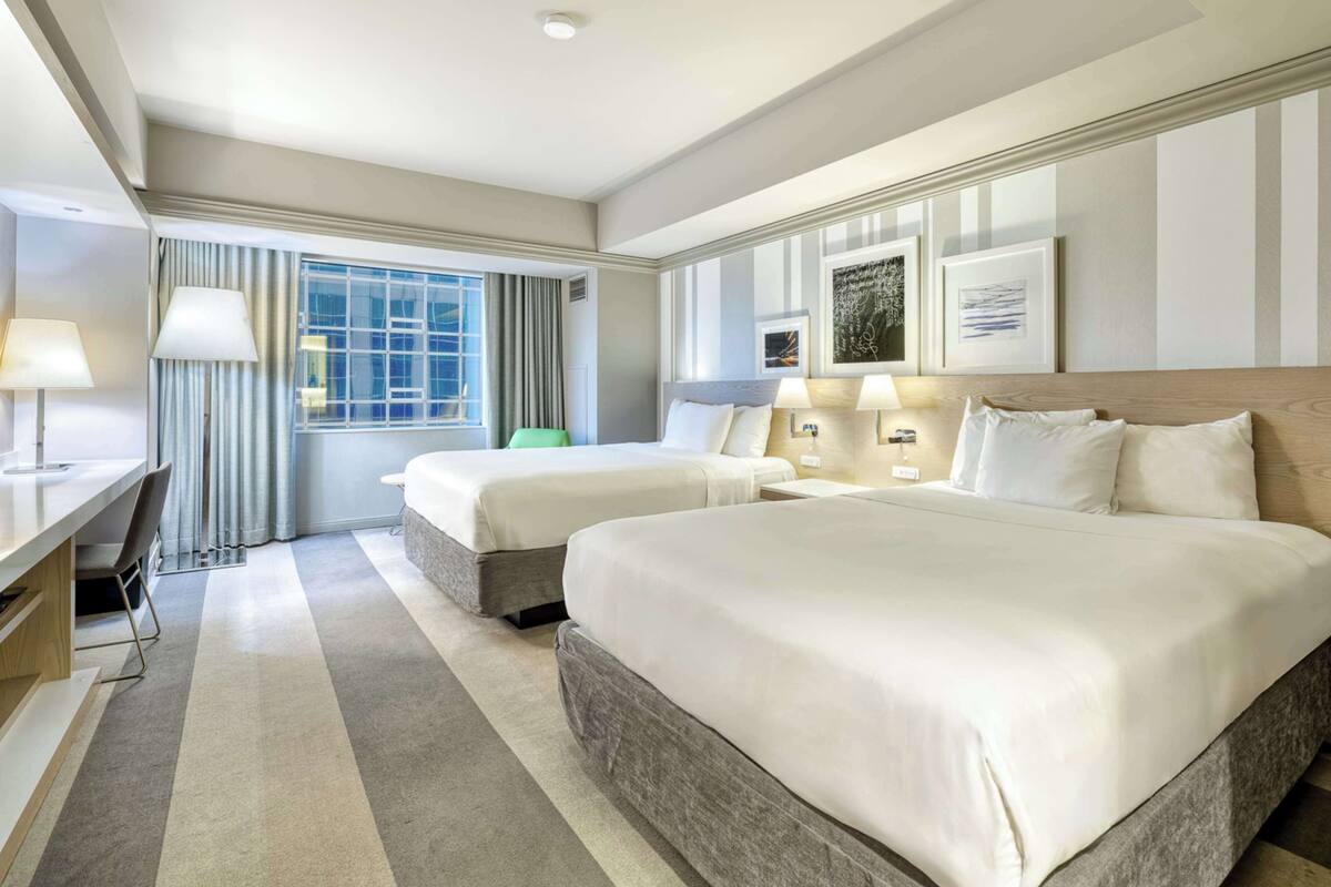 A hotel room with two beds, a desk, and a chair.