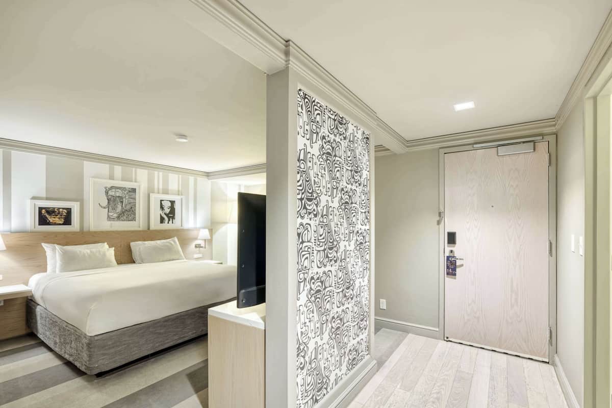 A hotel room with a bed, bedside table, and a large patterned wall divider.
