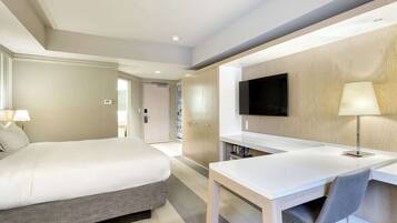 Una habitación de hotel moderna con una cama, un escritorio, una silla, un televisor y una lámpara.