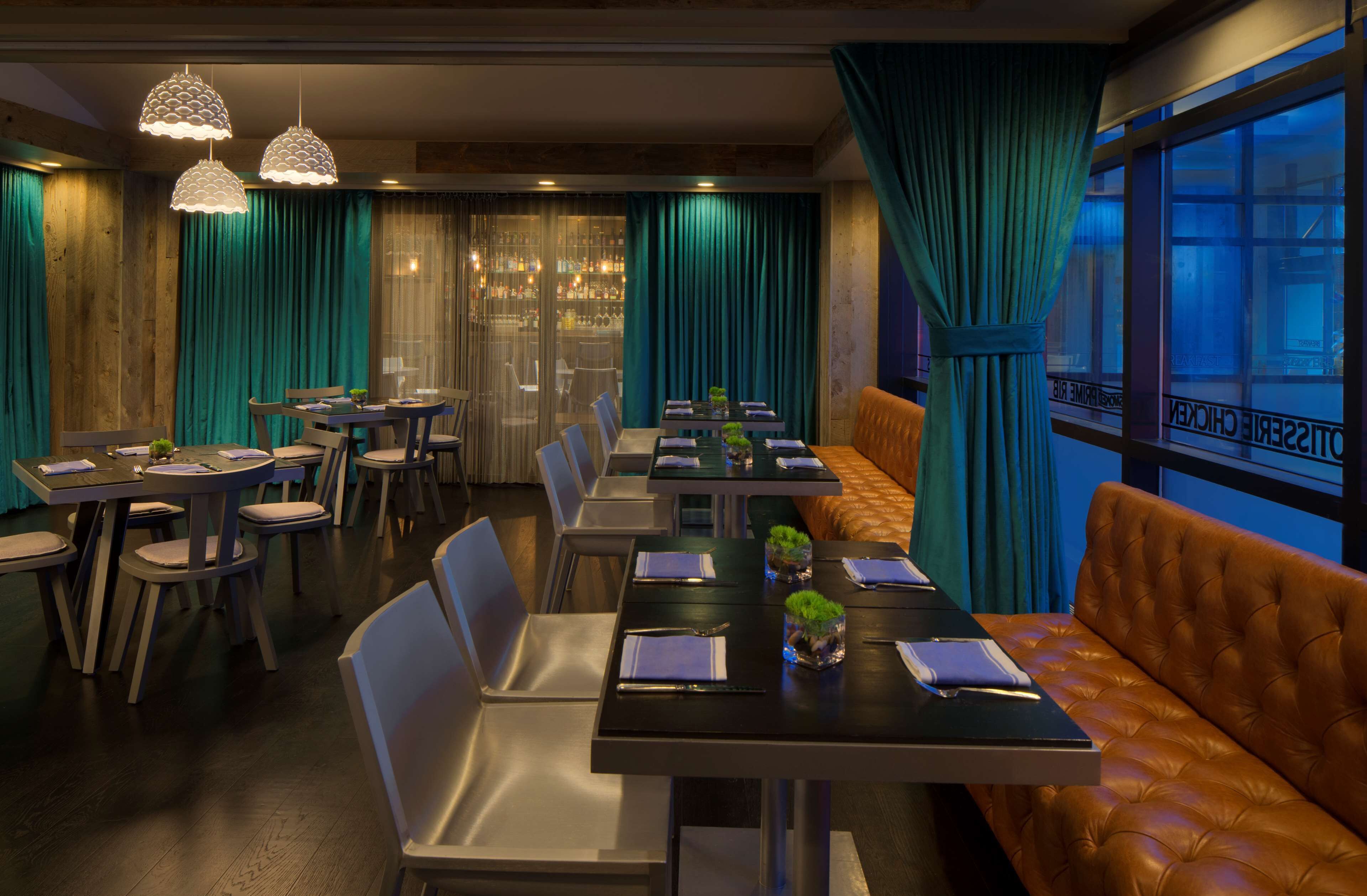 Un restaurant doté de nombreuses tables et chaises, d’un bar et d’un espace salon avec un canapé.