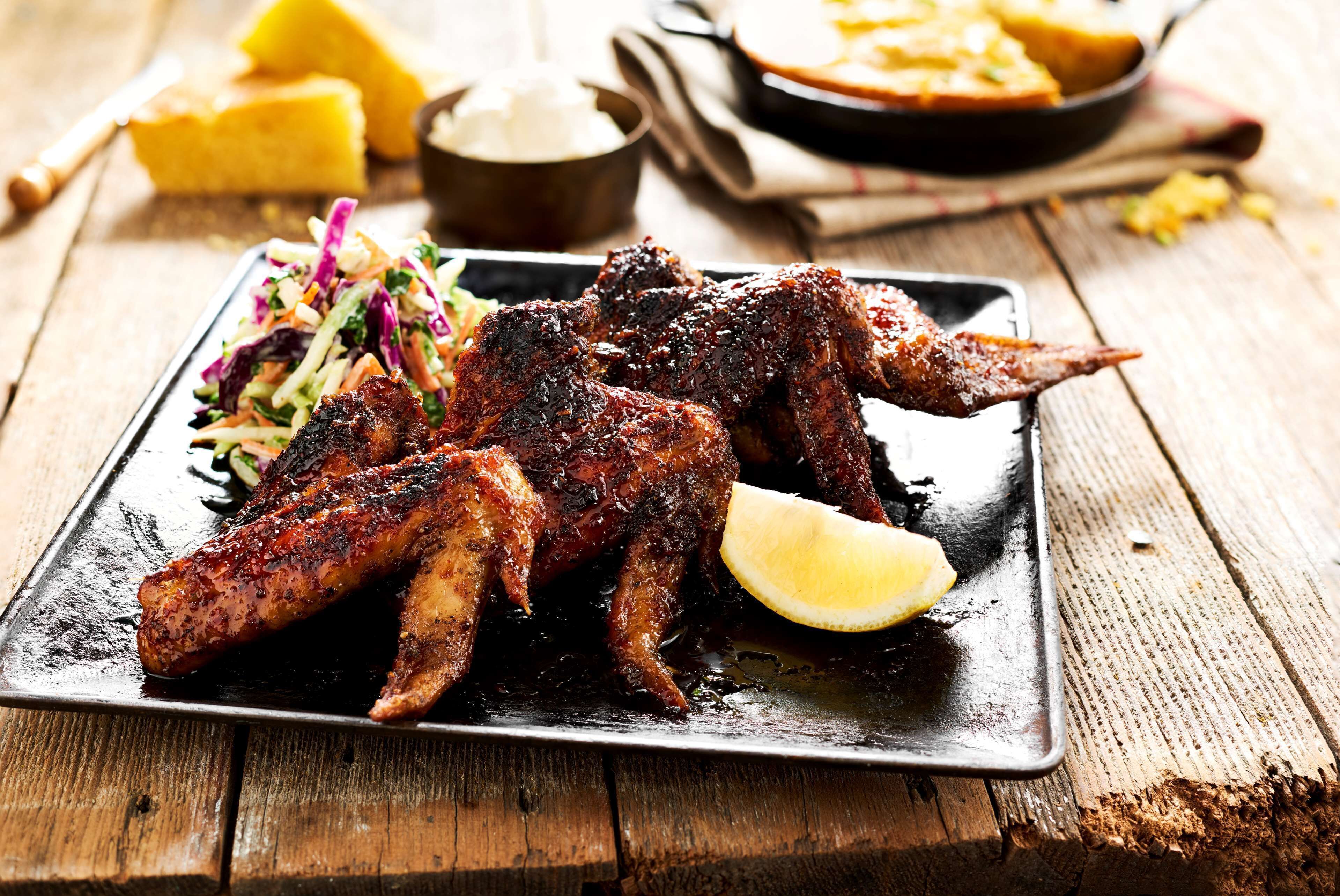 A plate of grilled chicken wings with a side salad and lemon wedge.