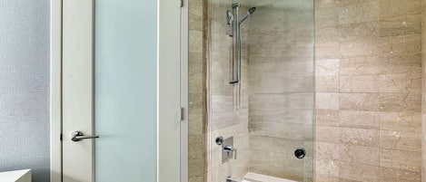 Un baño con cabina de ducha de vidrio, una bañera blanca y una puerta de vidrio satinado.