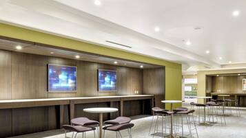 A modern bar area with high stools and a long counter, featuring recessed lighting and a neutral color palette.