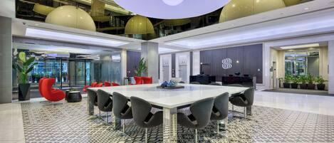 Une salle de conférence moderne, dotée d’une grande table, de chaises grises et d’un luminaire au plafond au design original.