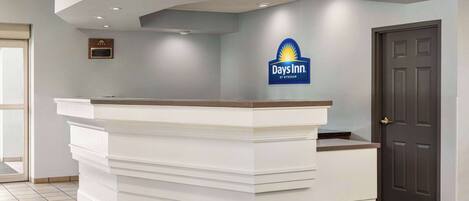 A reception desk with a logo, a door, and a tiled floor.