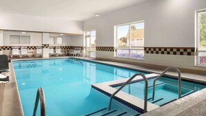 An indoor swimming pool with clear blue water, tiled walls, and a checkered pattern near the windows. - Days Inn by Wyndham Hershey (Hershey)