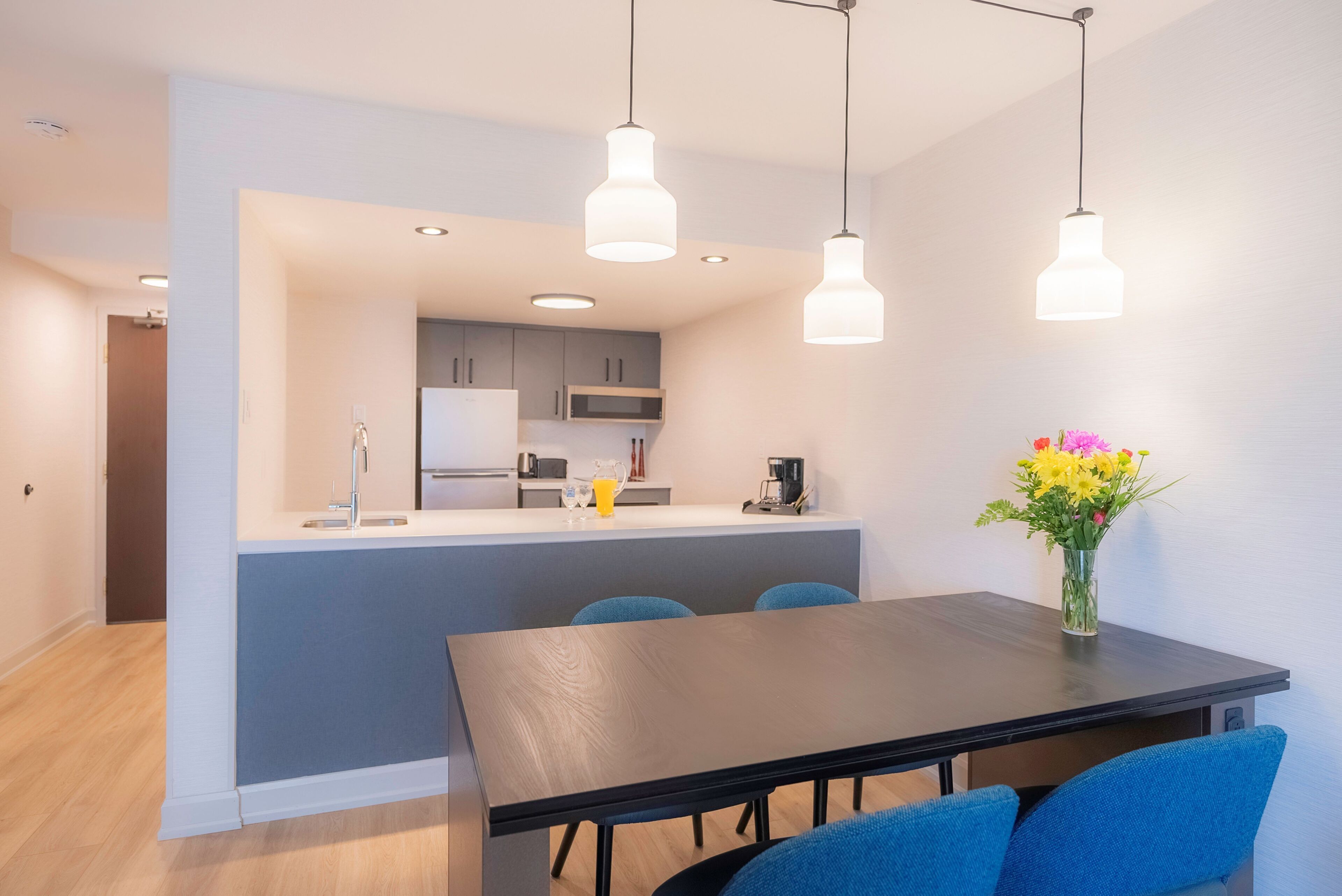 Una cocina moderna con una isla central, sillas azules y una mesa de comedor.