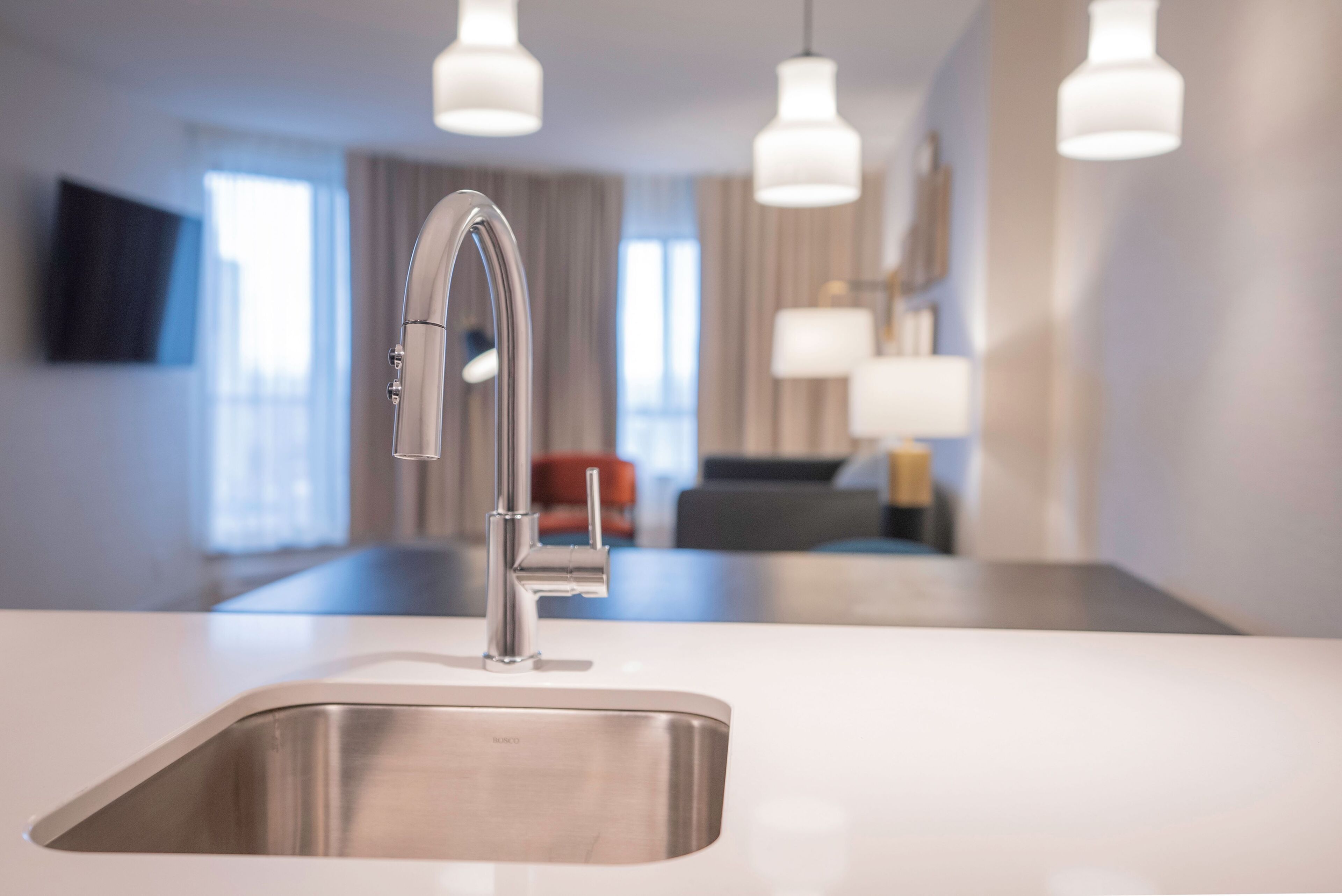 A modern kitchen with a stainless steel sink, a sleek faucet, and pendant lighting.