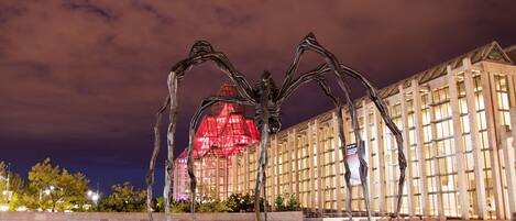 A large metal sculpture of a spider in front of a building with a glass facade.
