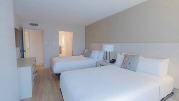 A hotel room with two beds, a desk, and a lamp.
