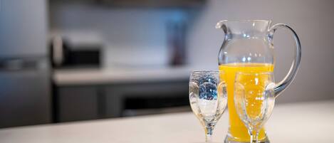 Un comptoir de cuisine avec une carafe de jus d’orange et un verre.