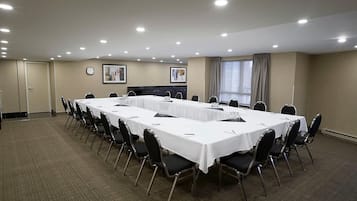 A conference room with a long table, chairs, a clock, and framed pictures on the walls.