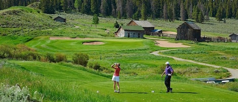 Un campo de golf con búnkeres, un tee y un putting green.