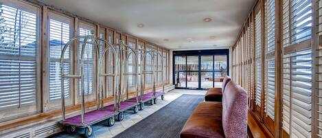 A hotel lobby with a long bench, a reception desk, and a row of luggage carts.