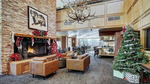 A spacious lobby with a fireplace, leather sofas, a Christmas tree, and a large chandelier.