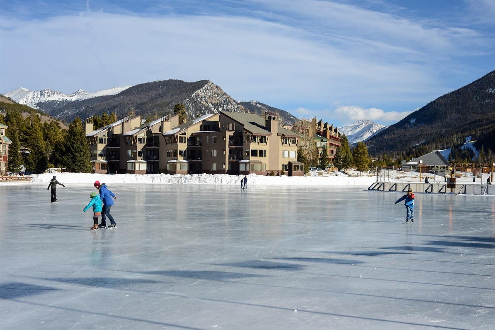 A large indoor ice skating rink with multiple levels of buildings in the background.