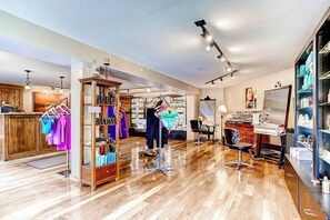 Un salón con pisos de madera, una estación de lavado de cabello y estantes con productos para el cabello.