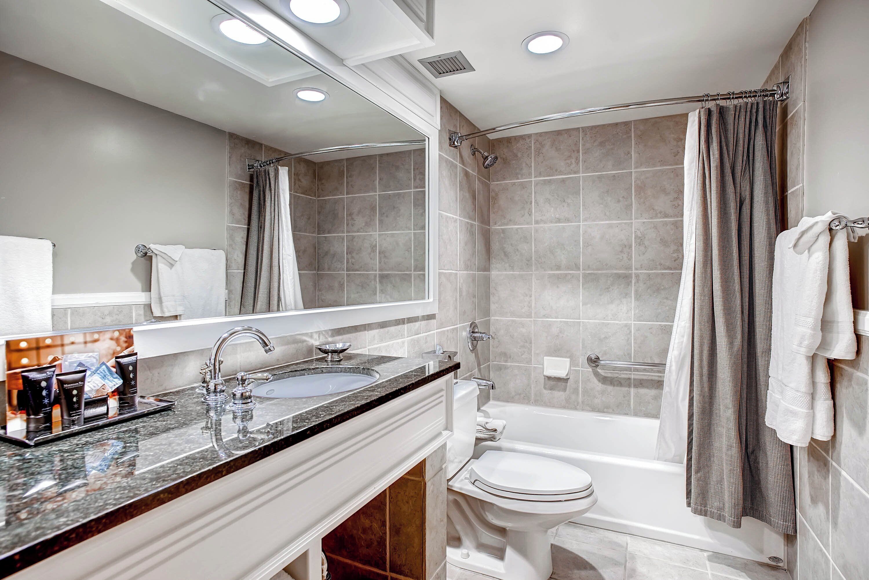 A modern bathroom with a sink, mirror, and bathtub.
