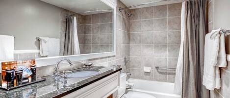 A modern bathroom with a sink, mirror, and bathtub.