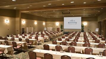 A large conference room with rows of tables and chairs, a screen displaying 'Keystone Lodge & Spa', and a carpeted floor.