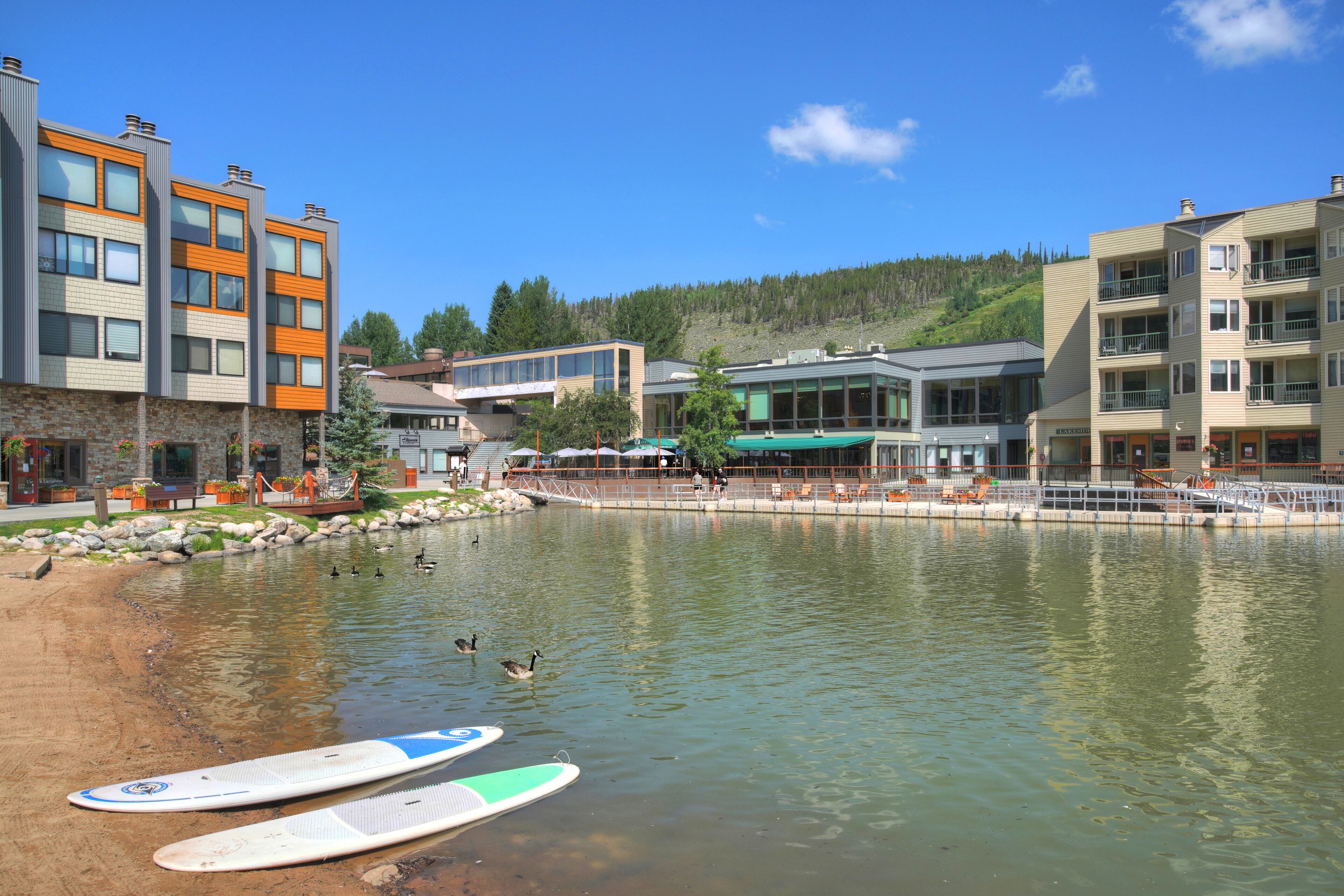 Un hotel junto al lago con varios pisos, terraza exterior y muelle para actividades acuáticas.