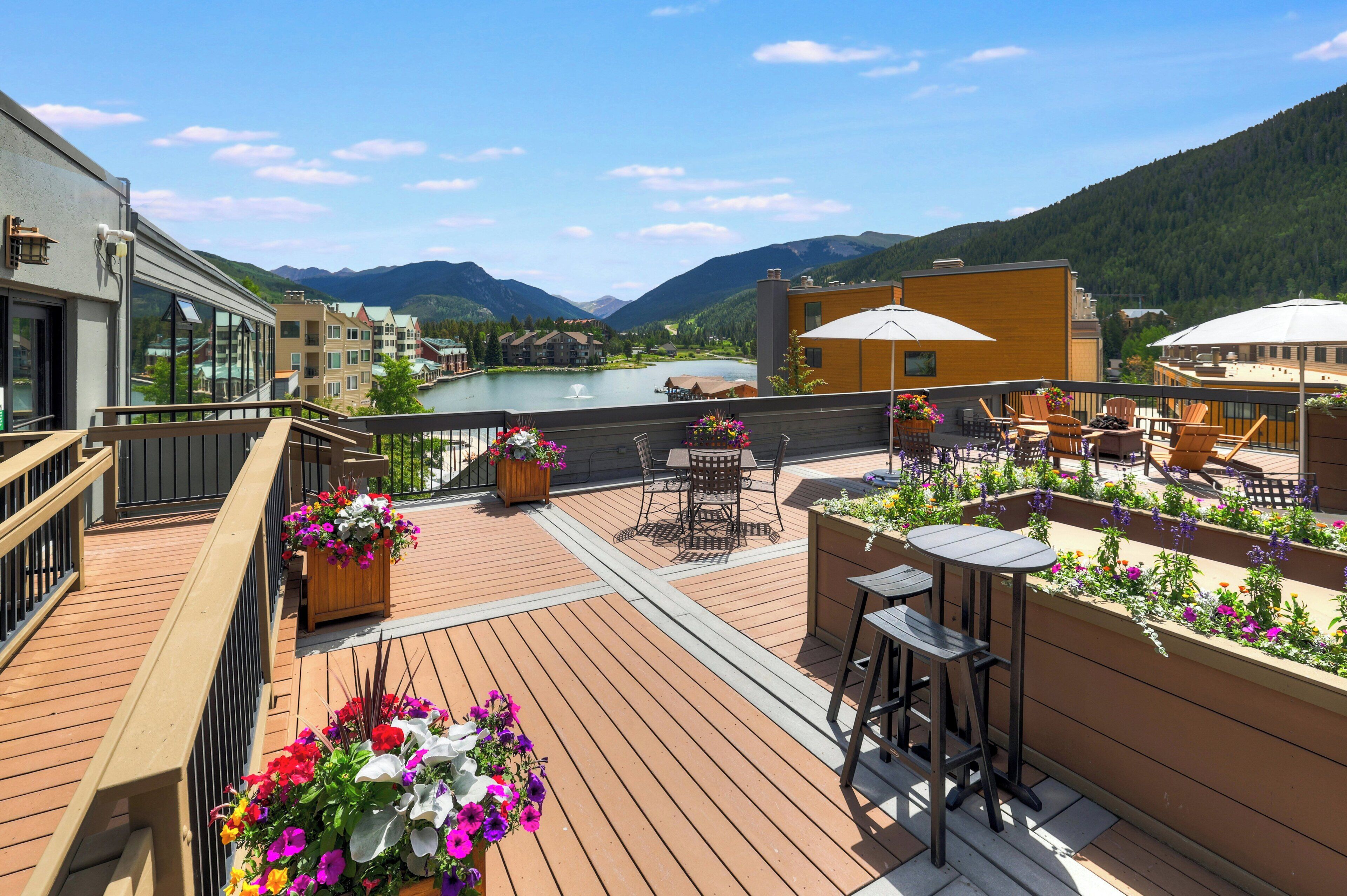 Une terrasse en bois avec des sièges extérieurs, une vue sur un lac et des montagnes en arrière-plan.