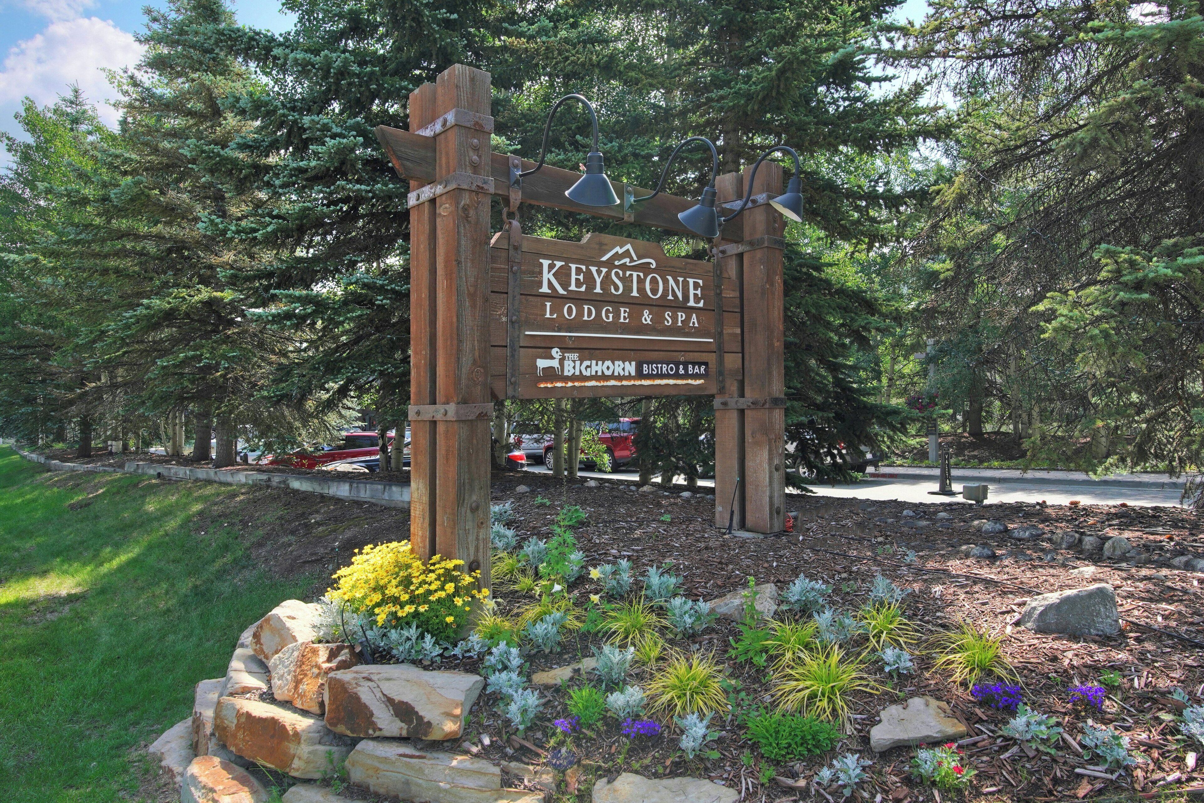 A wooden sign for Keystone Lodge & Spa with a landscaped garden in front.