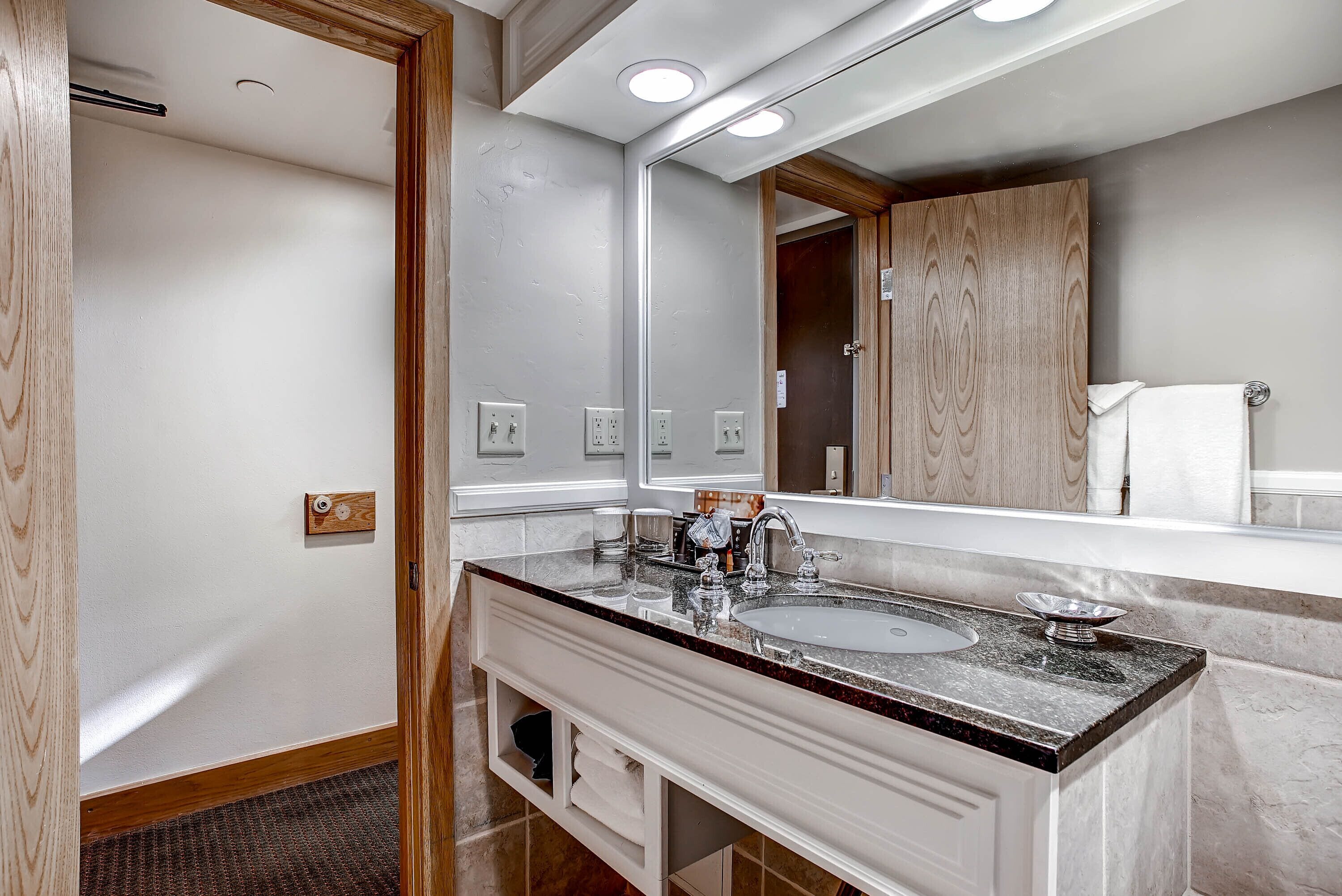 Une salle de bain moderne avec un grand miroir, deux lavabos et un meuble-lavabo avec espace de rangement.