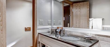 Une salle de bain moderne avec un grand miroir, deux lavabos et un meuble-lavabo avec espace de rangement.