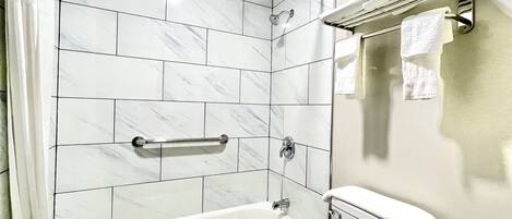 Un baño con bañera, toallero y cabezal de ducha.