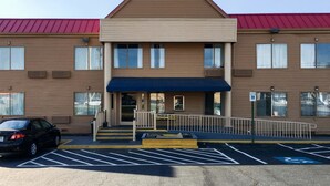 A two-story building with a red roof, a blue awning, and a parking lot with marked spaces.