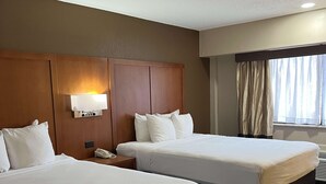 A hotel room with two beds, a wooden headboard, a bedside table with a phone, and a window with curtains. - SureStay Plus by Best Western Mobile I-65 (Mobile)