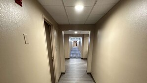 A long, narrow hallway with a patterned carpet, beige walls, and a ceiling with recessed lighting. - SureStay Plus by Best Western Mobile I-65 (Mobile)