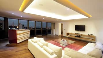 Una sala de estar moderna con un sofá, una mesa de centro de vidrio y un televisor de pantalla plana montado en la pared.