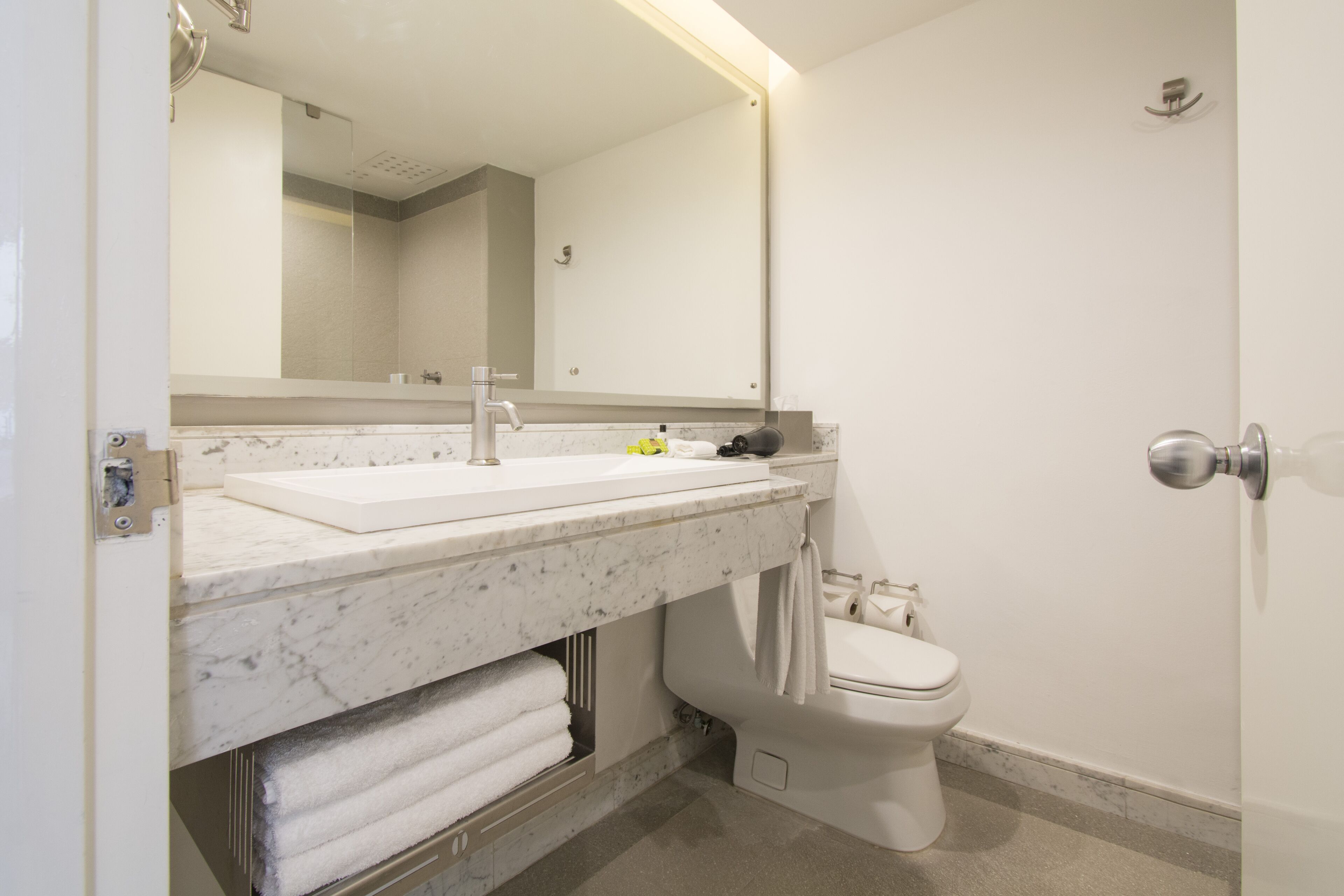 Un baño con lavamanos, espejo y retrete blancos.