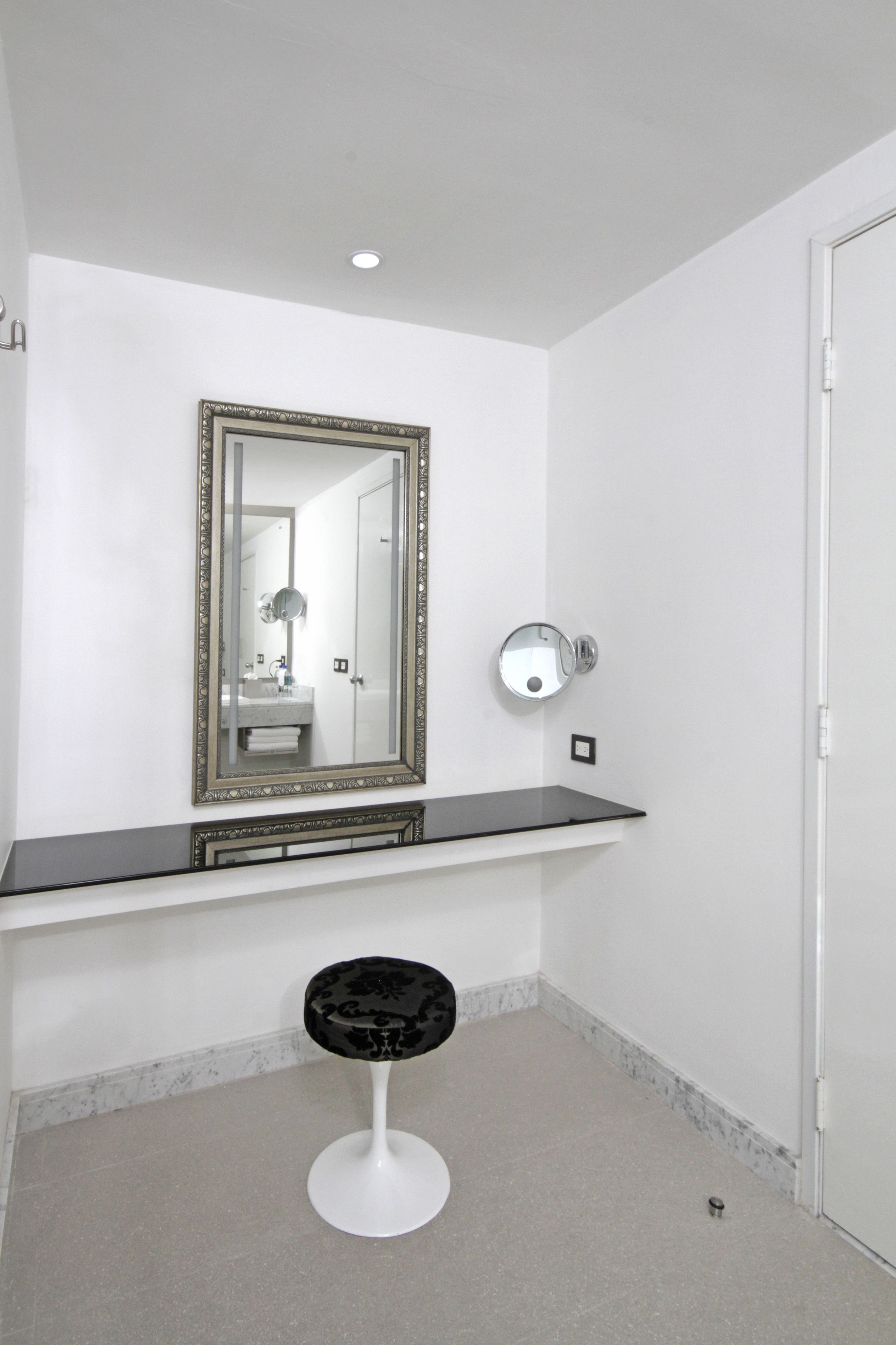 A bathroom with a large mirror, a vanity, and a stool.